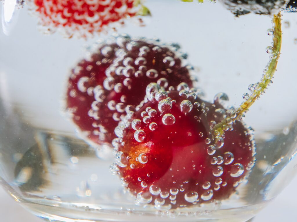 Cherries with air bubbles on them submerged in water